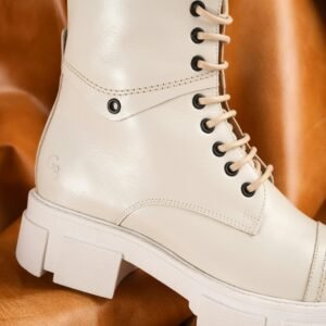 Elegant beige leather boot with lace-up design showcased on a rich brown background.