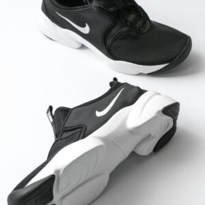 From above of sports shoes pair with black breathable surface and white soles comfortable suiting on feet placed on white background