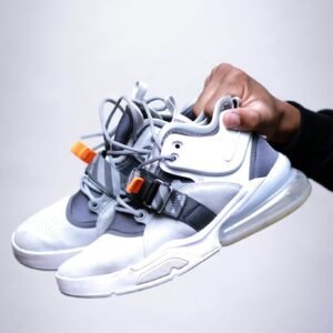 Modern white and grey sneakers being held, showcasing contemporary footwear design.